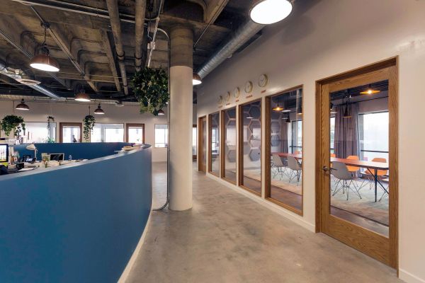 Modern office space with glass meeting rooms and blue partition.