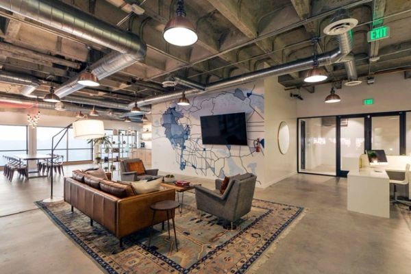 Modern industrial-style office lounge area with leather sofa and wall art.