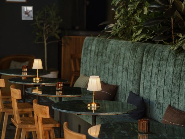 Cozy café seating with wooden chairs and green velvet bench.