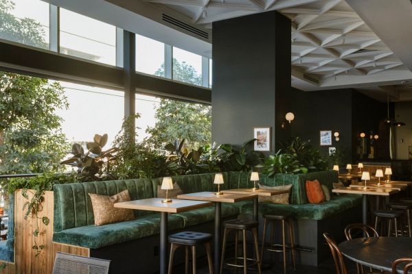 Cozy modern restaurant seating with green velvet benches and natural light.