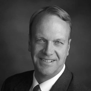Black and white portrait of a smiling man in a suit and tie.
