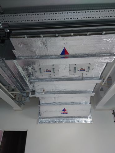 Ceiling ductwork wrapped in shiny insulation material.
