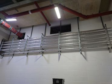 Industrial metal railing installed on a white brick wall.