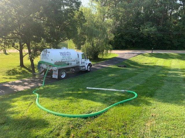 White truck with green hose on grassy lawn.