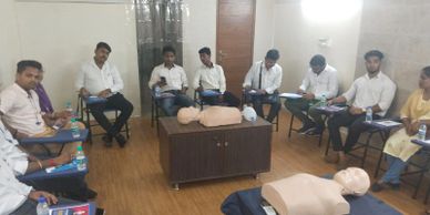 Group of students in a classroom with CPR mannequins for training.