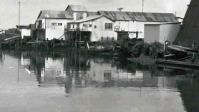 Black and white photo of old buildings along a calm waterfront.