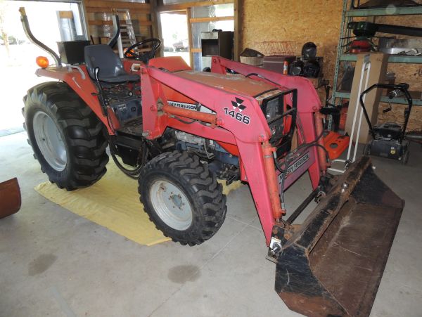Red Massey Ferguson tractor with front loader inside a garage.