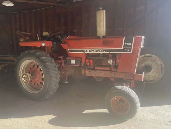 Red International 766 tractor parked inside a barn.