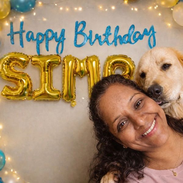 Woman smiling with a dog at a birthday celebration.