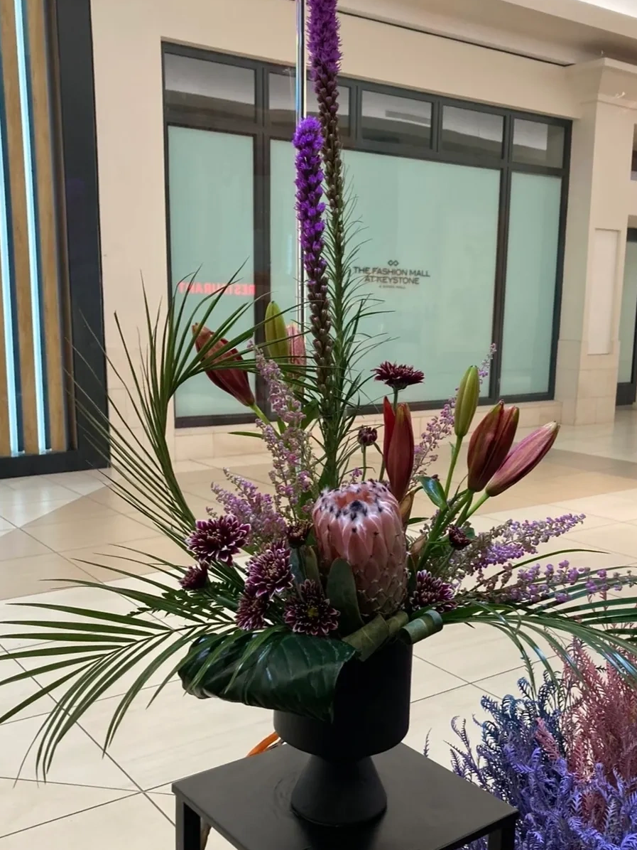 Elegant floral arrangement with purple and pink flowers in a black vase indoors.
