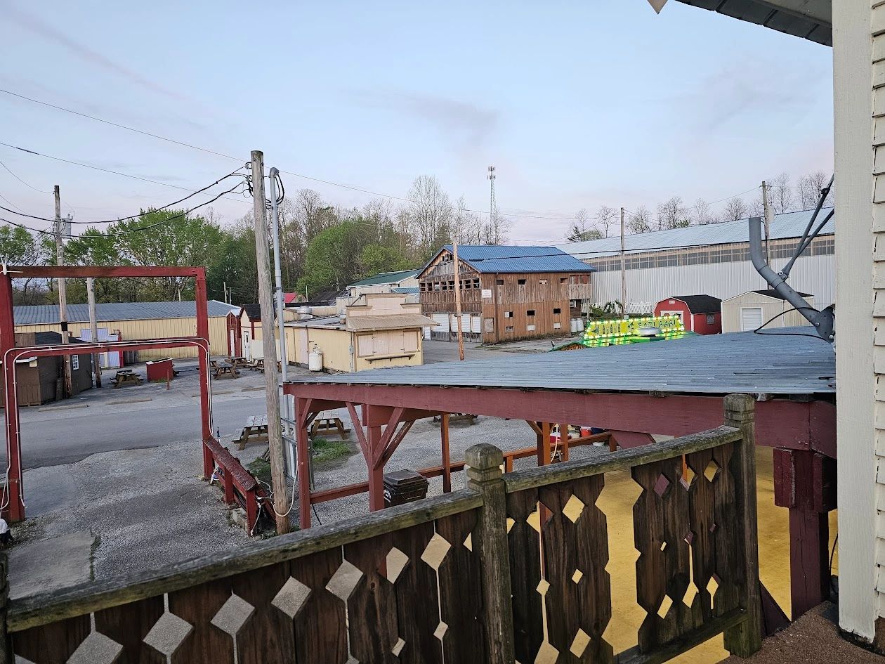 View of an empty rustic outdoor area with wooden structures and sheds under a clear sky.