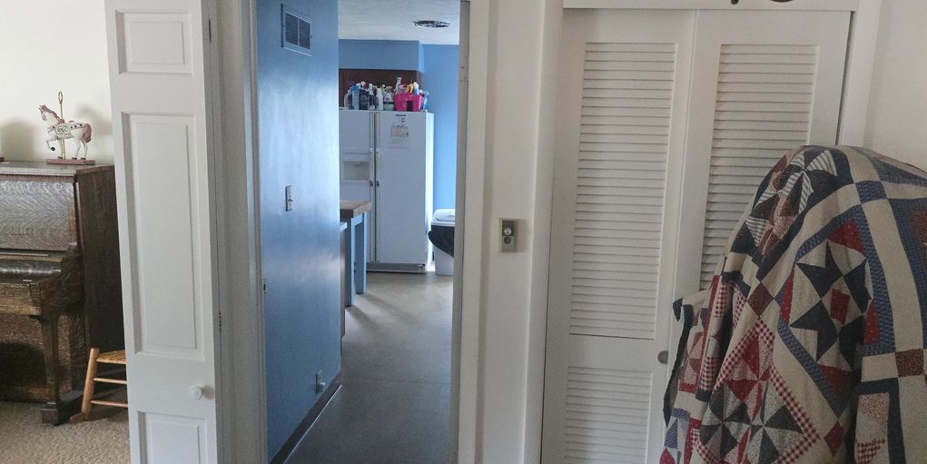 View through a doorway into a kitchen with a refrigerator and a blue wall.