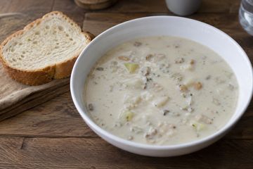 Bowl of creamy clam chowder soup with bread.