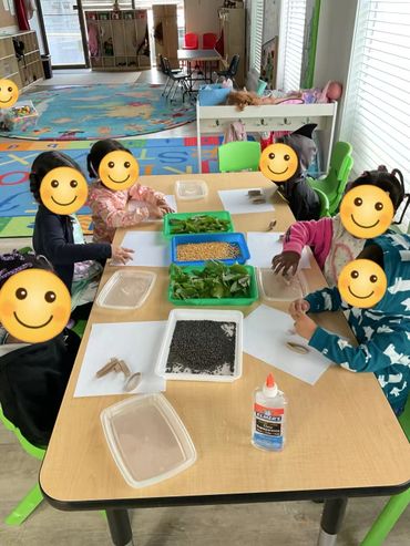 Children engaged in a craft activity with natural materials at a classroom table.