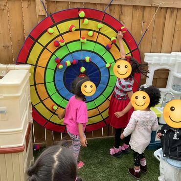 Children playing a colorful ball toss game outdoors.