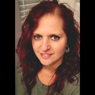 A woman with curly red hair smiling at the camera.