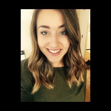 Smiling woman with wavy hair wearing a green sweater.