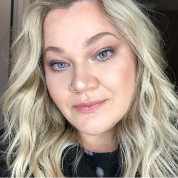 Blonde woman with soft makeup and wavy hair.
