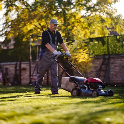 Man mowing lawn during sunset.