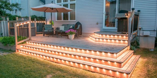 Cozy wooden deck with warm string lights and outdoor seating.
