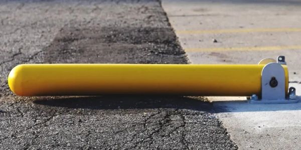 Yellow parking barrier on asphalt surface.