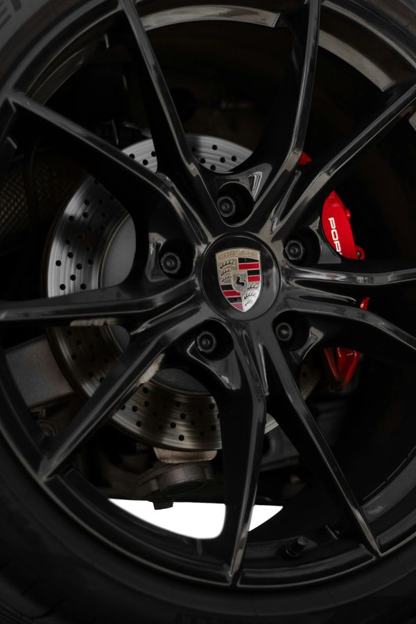 Close-up of a Porsche black alloy wheel with red brake caliper.