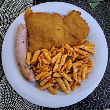 Plato con milanesa, pasta con salsa y salchicha.