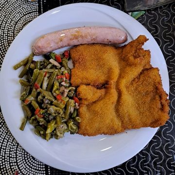 Plato con salchicha, milanesa y verduras.