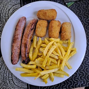 Plato con salchichas, croquetas y papas fritas.
