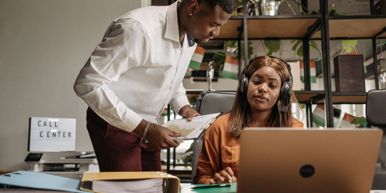 Two call center employees working together at a desk.