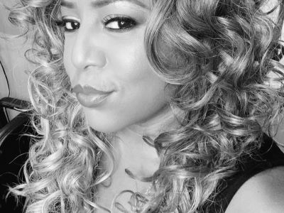 Close-up black and white portrait of a woman with curly hair.