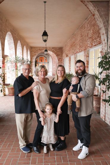 A happy multigenerational family posing together in a rustic brick hallway.