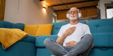 Elderly man meditating with headphones on a cozy sofa.