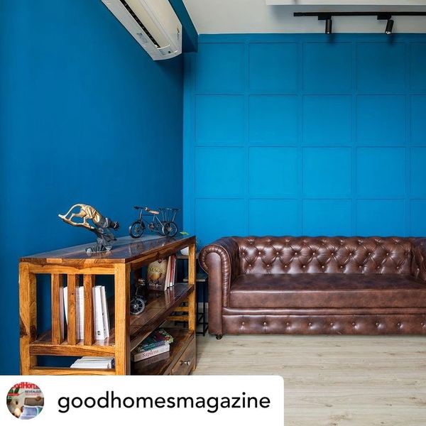 Chesterfield sofa design in tan brown leatherette placed in a deep blue colored room