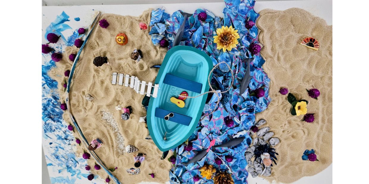 Miniature beach scene with a boat, sand, and sea creatures.