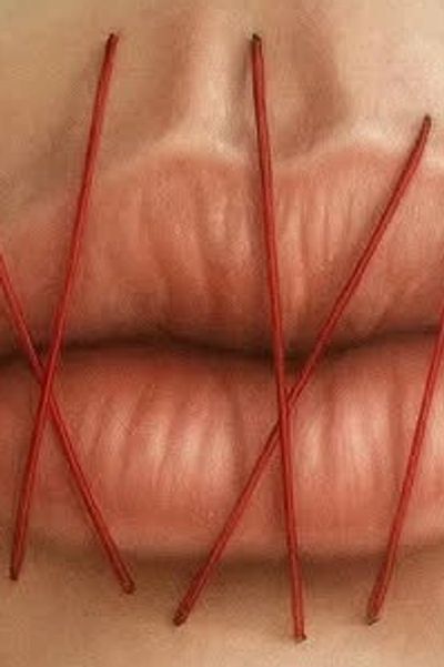 Close-up of lips sewn shut with red thread.
