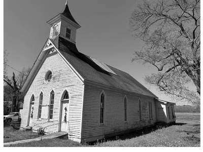 Black and white photo of a wooden church with a steeple and large trees.