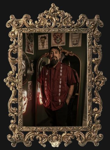 Man posing in an ornate gold mirror frame.