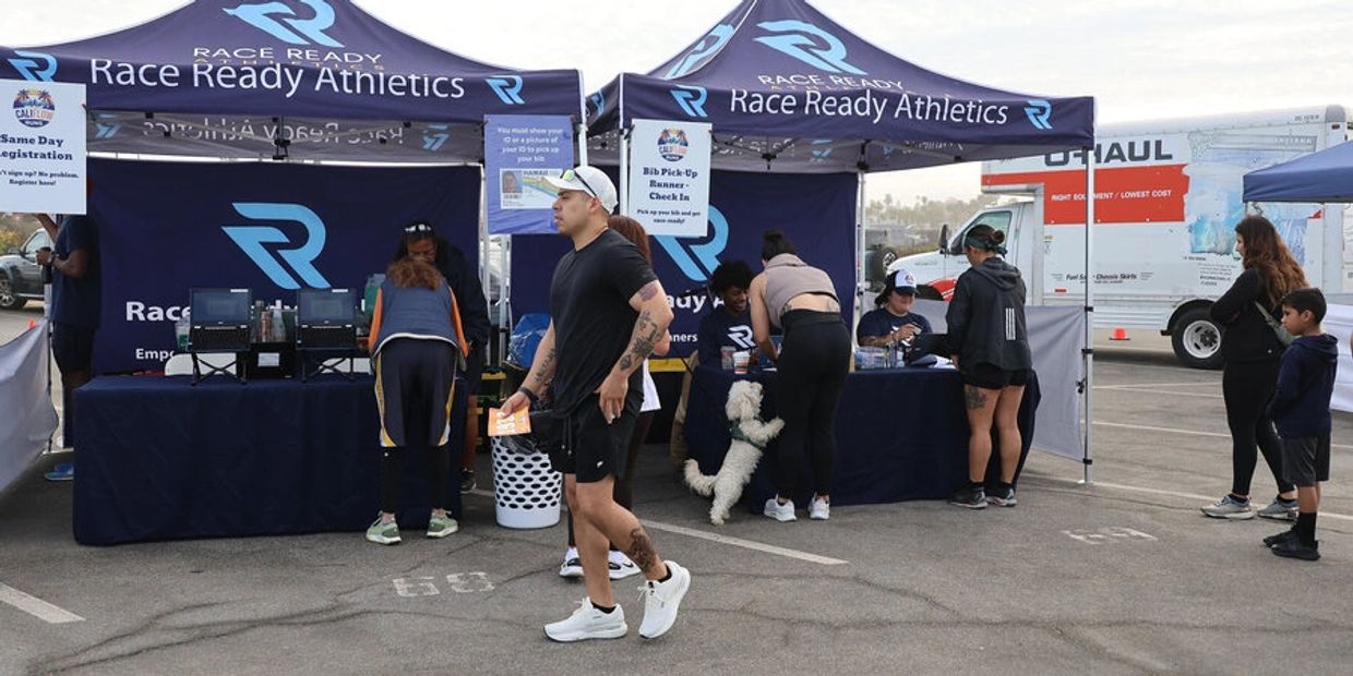 People registering at Race Ready Athletics tents in a parking lot.