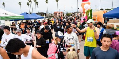 Runners gather at an outdoor event near palm trees and a large inflatable reindeer.