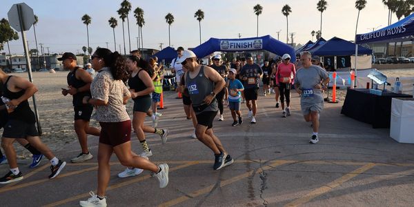 Runners approaching the finish line of a beachside race event.
