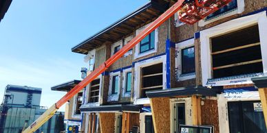 Construction workers install windows on a multi-story building using a boom lift.