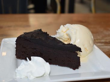 Rich chocolate cake slice with vanilla ice cream and whipped cream.