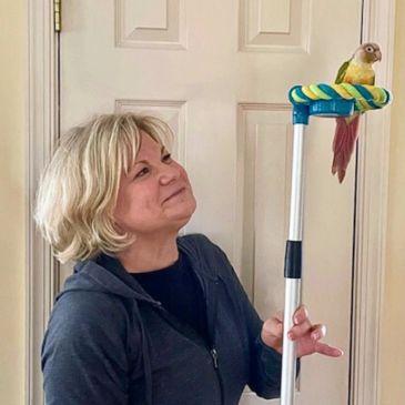 Woman smiling at a bird perched on a pole.