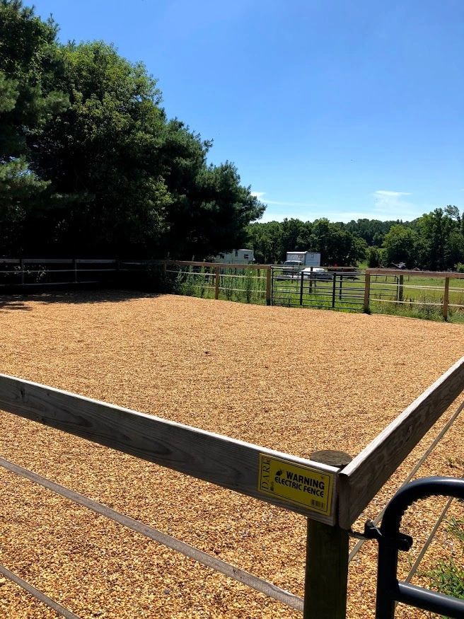 Electric fence around a gravel area in a rural setting.