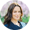 Professional woman with dark hair smiling outdoors.