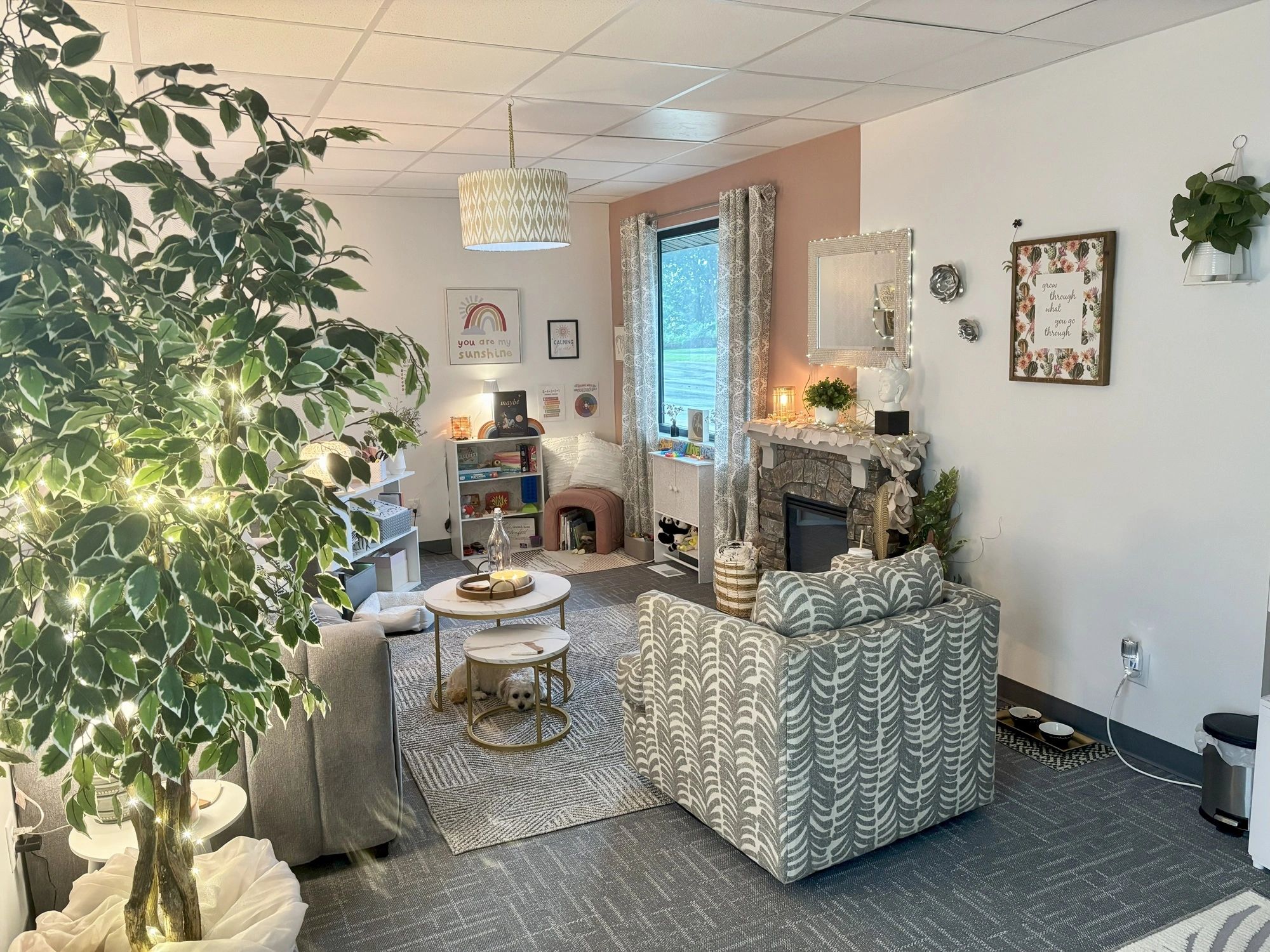Cozy living room with comfy chairs, a large plant, and warm lighting.