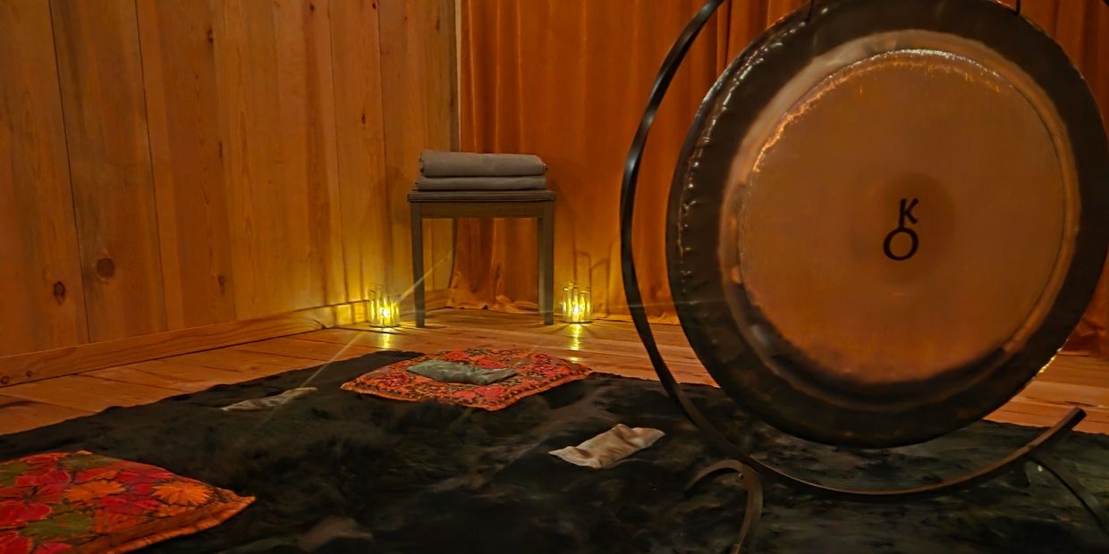 Cozy meditation room with a gong, cushions, and warm lighting.