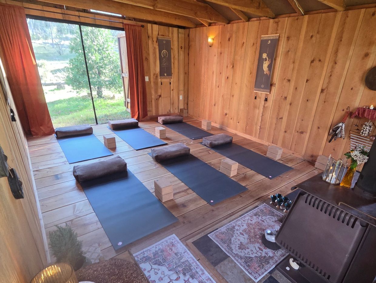 Cozy wooden yoga studio with mats, bolsters, and blocks set up for practice.