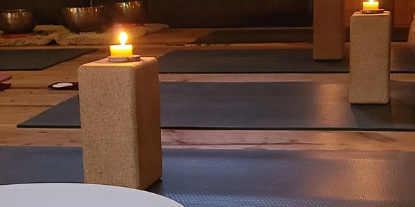 Candles lit on yoga blocks in a dimly lit room for meditation or yoga.